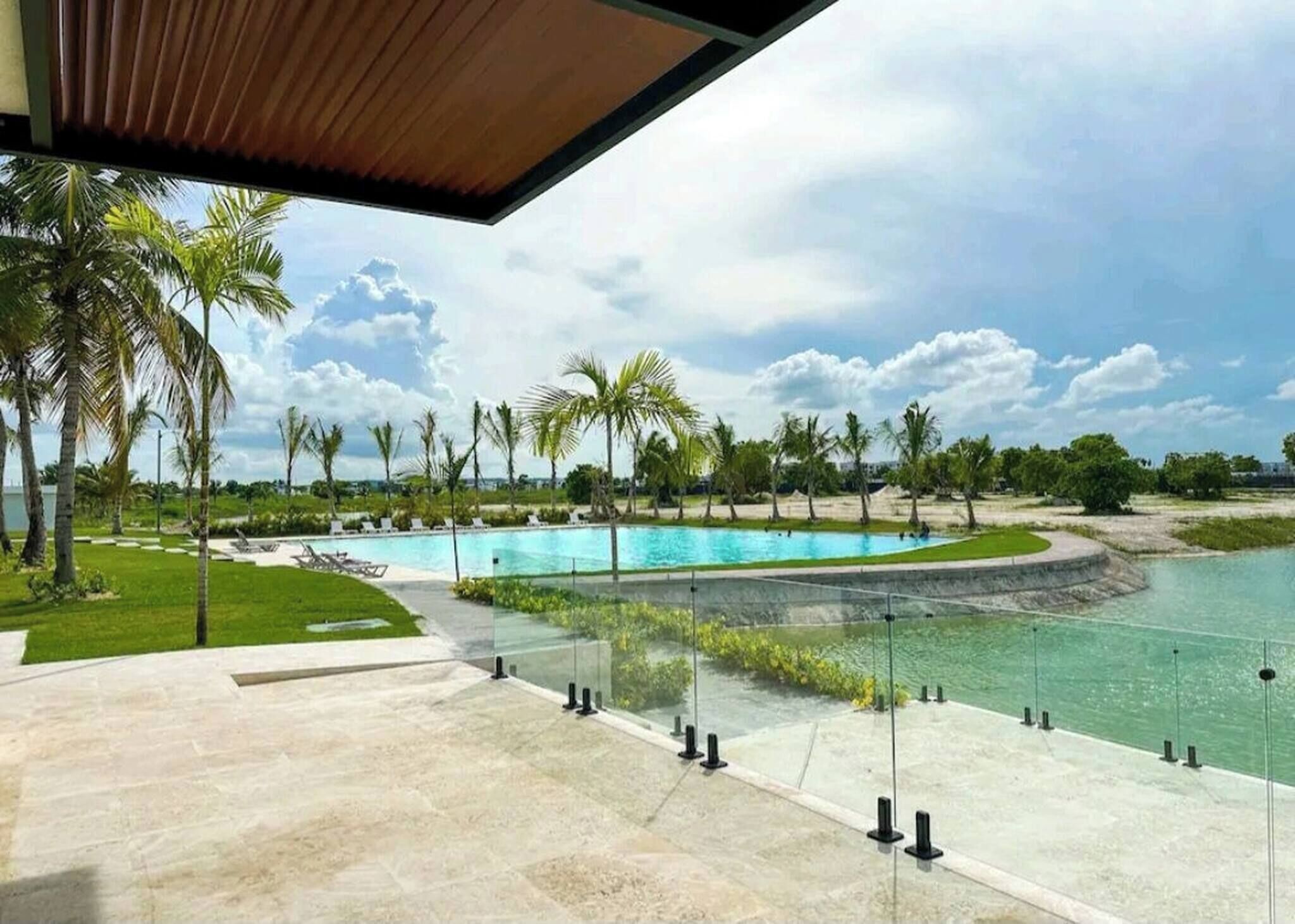 A pool area with clear water, surrounded by palm trees and a view of the sky.