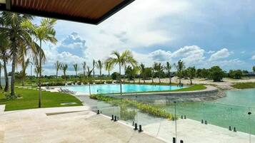 A pool area with clear water, surrounded by palm trees and a view of the sky.