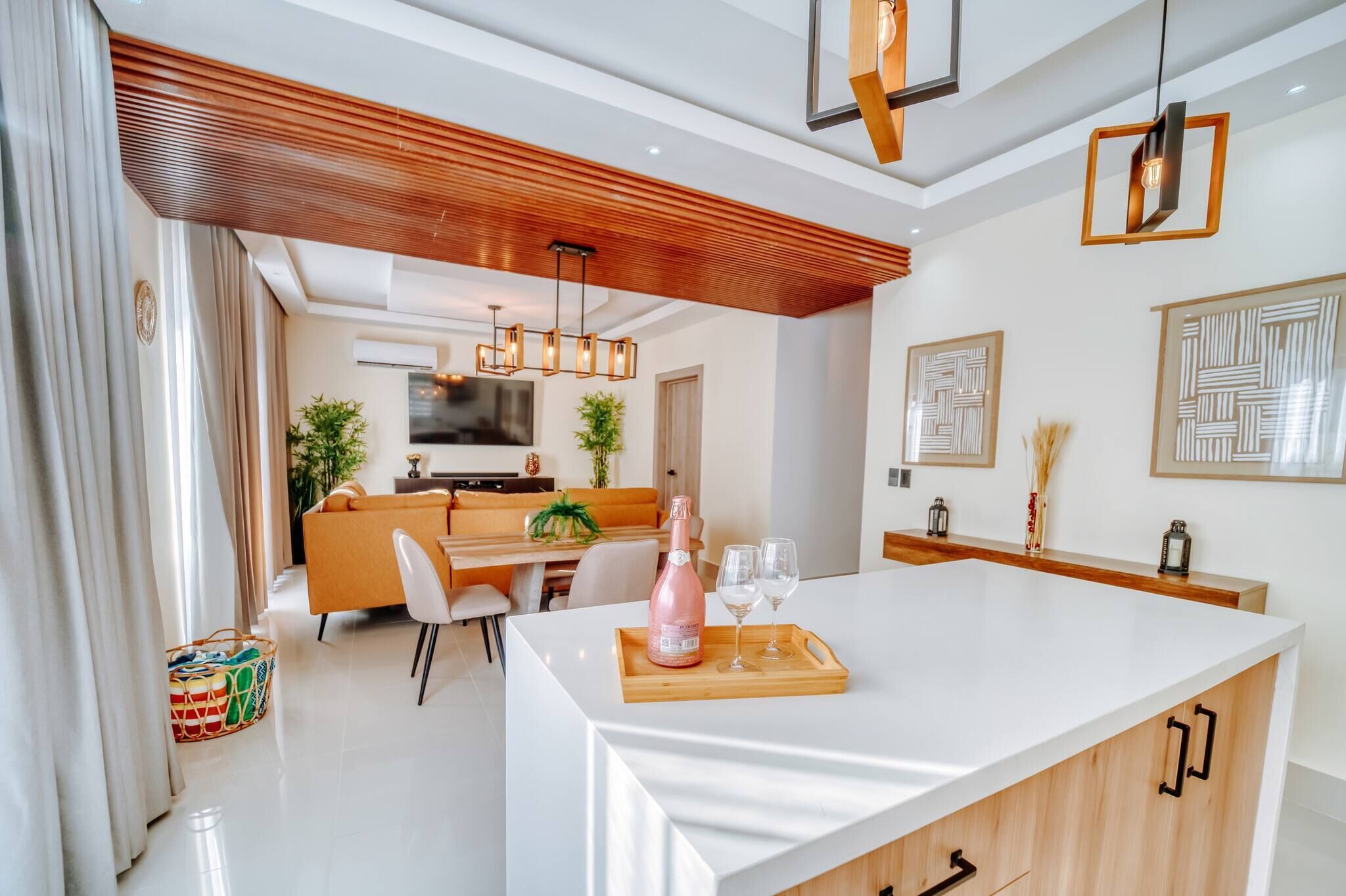 A modern kitchen with a central island, wooden ceiling, and pendant lighting.