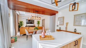 A modern kitchen with a central island, wooden ceiling, and pendant lighting.