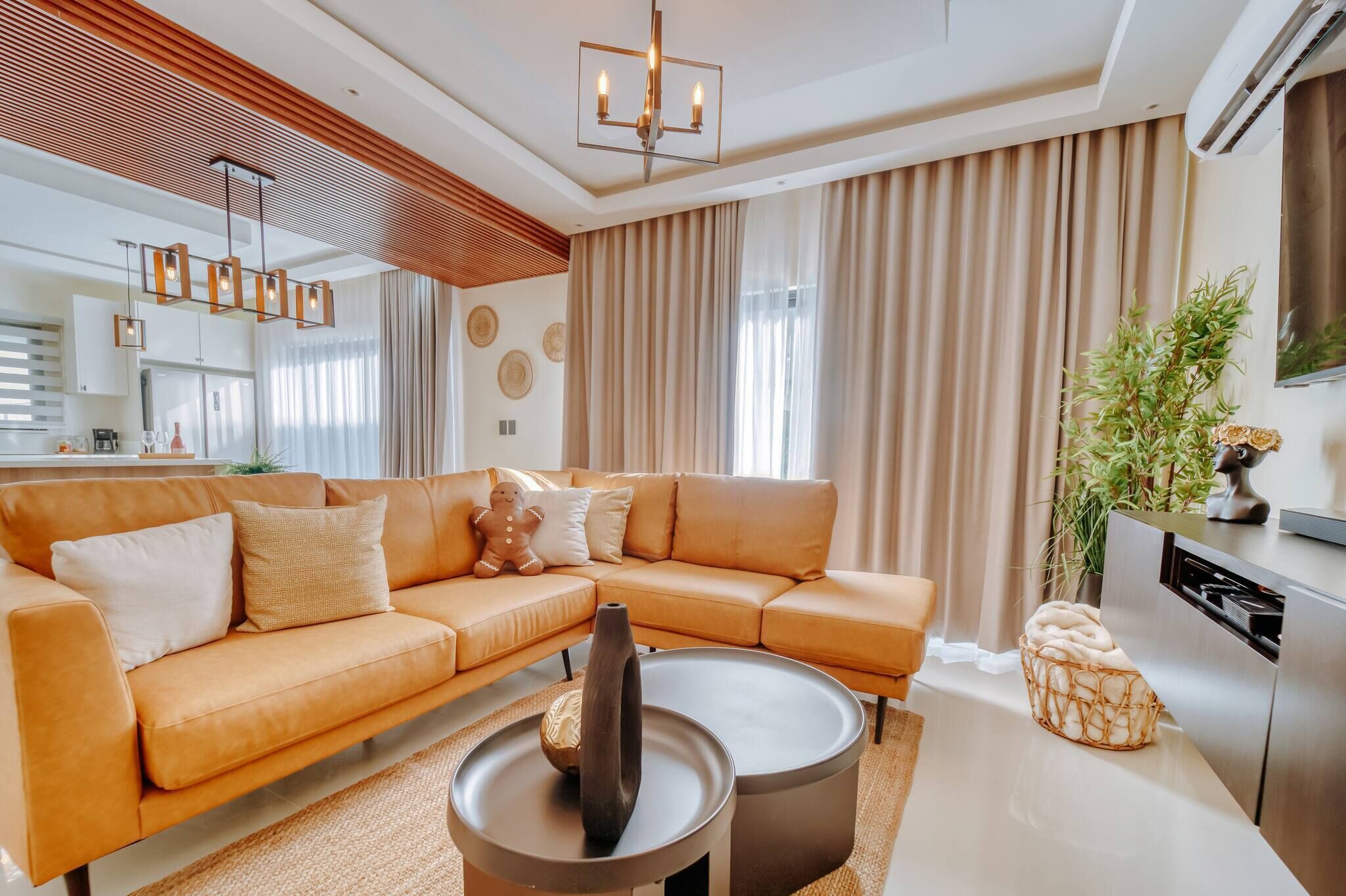 A modern living room with a sectional sofa, a round coffee table, and a kitchen area with a dishwasher.