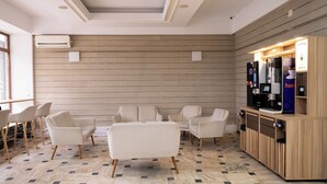 Un espace détente moderne, aménagé avec des canapés et des fauteuils, un coin café et un climatiseur fixé au mur.