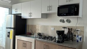 A modern kitchen with white cabinets, a stainless steel refrigerator, a microwave, and a gas stove. - Cozy 2-bedroom house in adorable Ahuachapan with AC / pool (Ahuachapan)