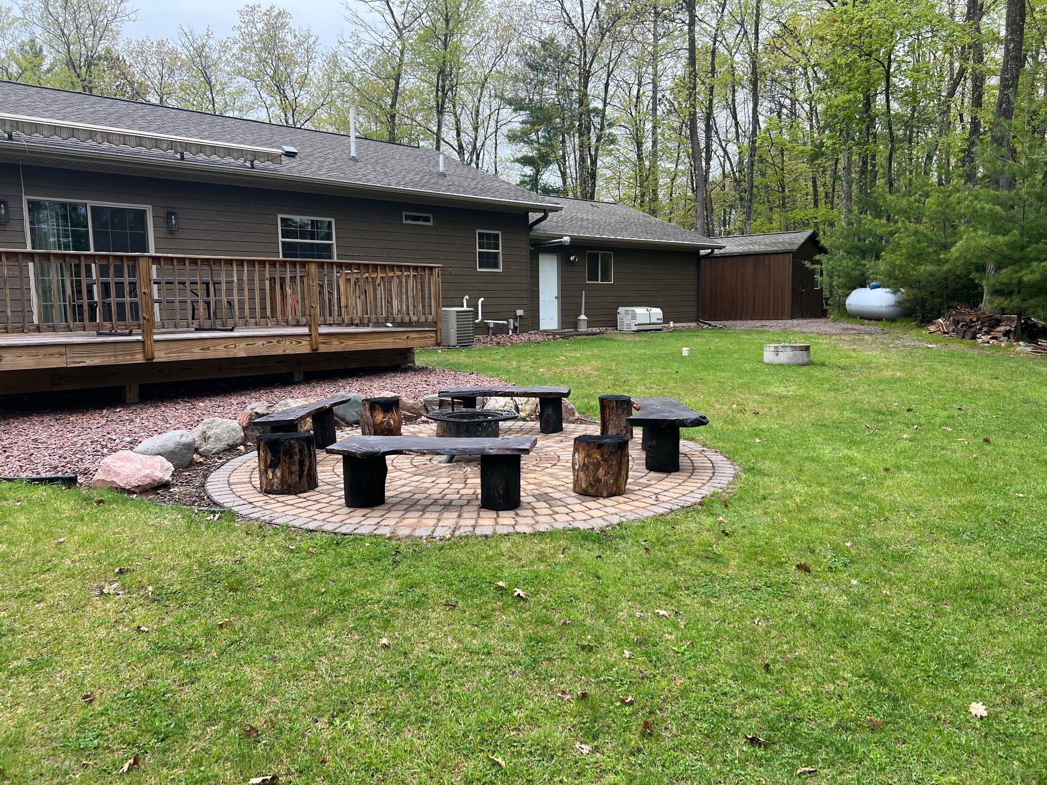 Un jardin avec un foyer, des sièges d’extérieur, une terrasse en bois et une maison.