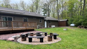 A backyard with a fire pit, outdoor seating, a wooden deck, and a house. - The Gathering Place, 3 BR sleeps 8, Near Hayward close to lakes and trails. (Hayward)