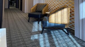 A modern hotel lobby with a patterned wall, two armchairs, a carpeted floor, and recessed lighting. - The Watergate Hotel Baku (Baku)