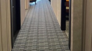 A hotel corridor with a patterned carpet, modern lighting, and a bench in the distance. - The Watergate Hotel Baku (Baku)