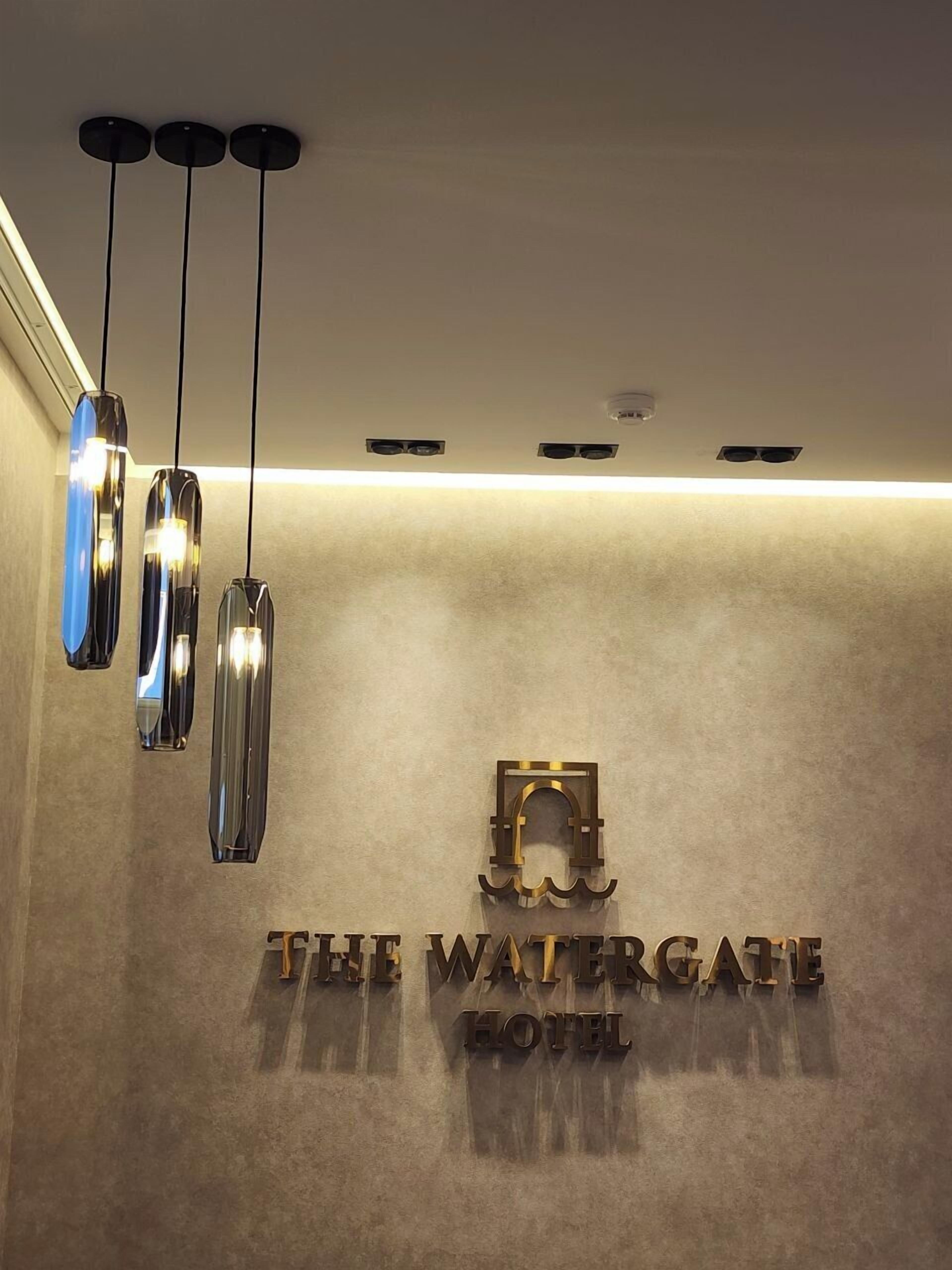 A hotel sign with the name "The Watergate Hotel" and a modern light fixture above it.