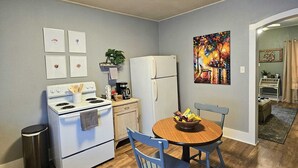 A compact kitchen with a stove, refrigerator, and dining table with chairs. - Lovely 2-bedroom downtown apartment in charming Lafayette (Lafayette)