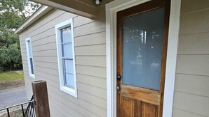 A house with a wooden front door, a welcome mat, and a small porch with a railing. - Lovely 2-bedroom downtown apartment in charming Lafayette (Lafayette)