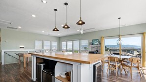 Een moderne keuken met een centraal eiland, houten vloeren en hangende lampen.