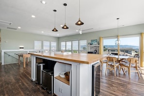 A modern kitchen with a central island, wooden flooring, and pendant lighting. - This Is It | Ocean Views, Walk to Park & Beach (Crescent City)