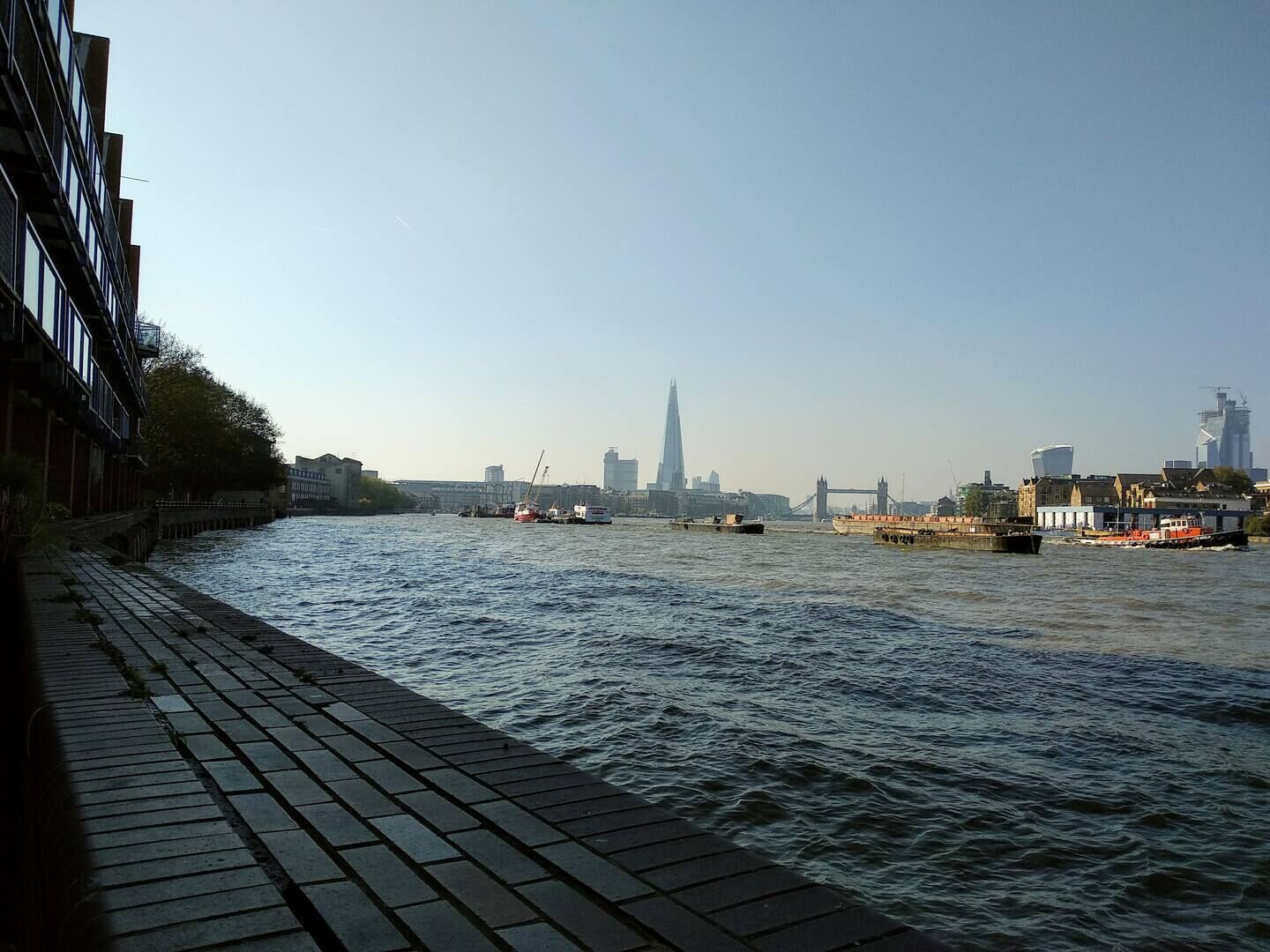 A river with boats, a bridge, and buildings in the background.