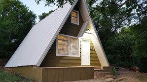 A small, triangular wooden cabin with a pitched roof, a front door, and a window. - Lakeside Cabin #4 (Eastland County)