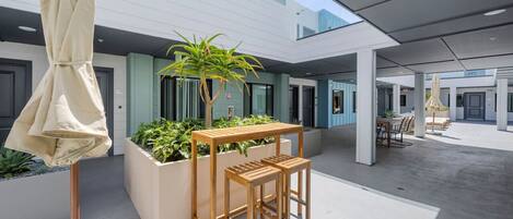 Ein moderner Außenbereich mit Holztisch und Stühlen, einem Blumentopf und einer überdachten Sitzgelegenheit.