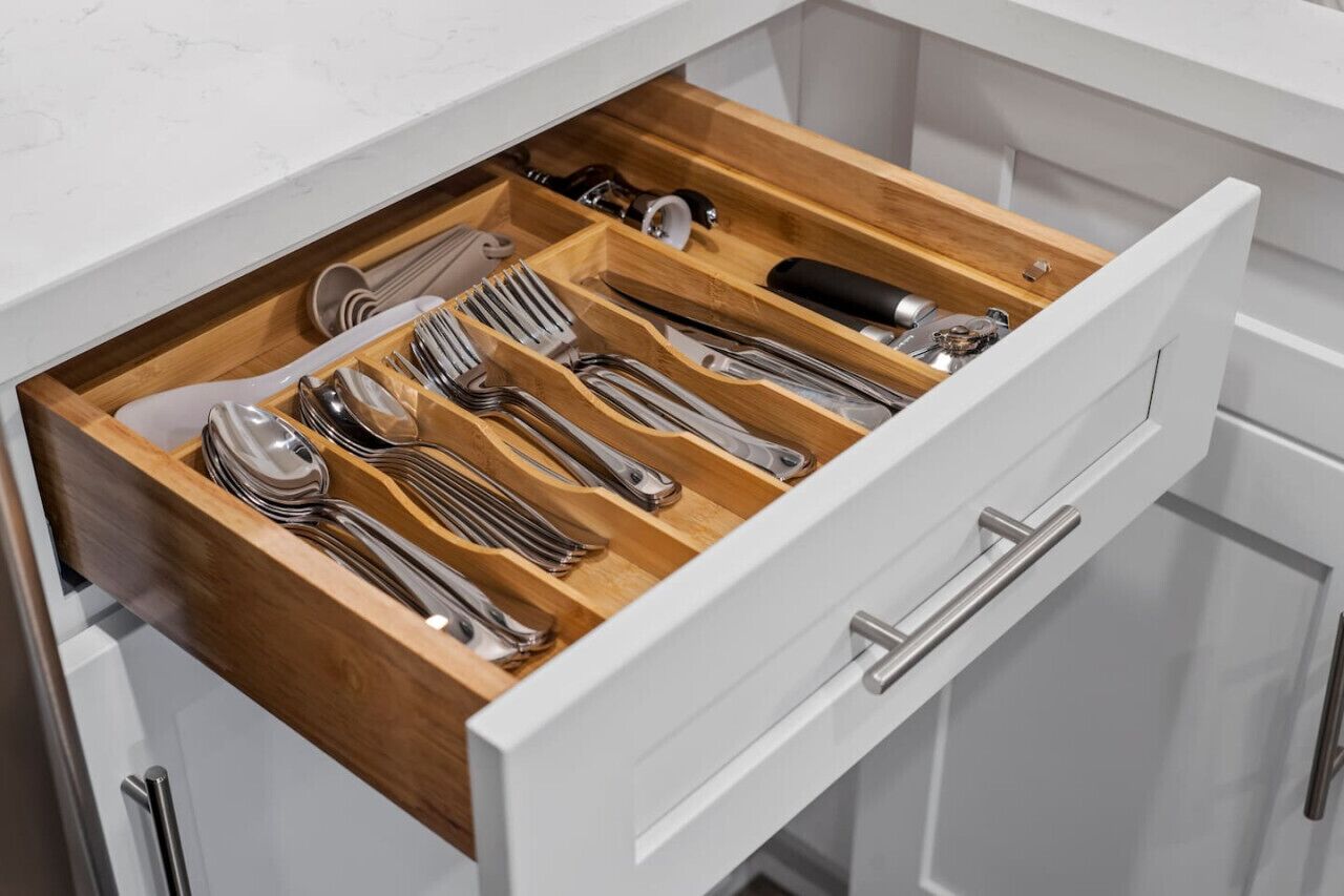 Un cajón con varios compartimentos que contiene distintos utensilios de cocina.