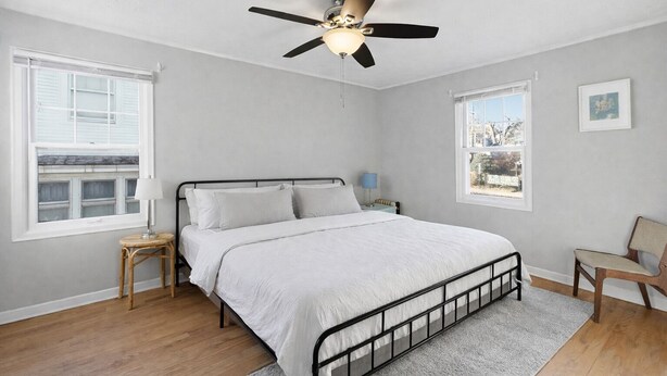 Une chambre à coucher avec un lit, un ventilateur de plafond, une fenêtre et une chaise.