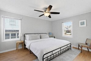 Ein Schlafzimmer mit einem Bett, einem Deckenventilator, einem Fenster und einem Sessel.
