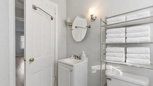Une salle de bain avec une porte blanche, un lavabo, un miroir, un porte-serviettes et des toilettes.