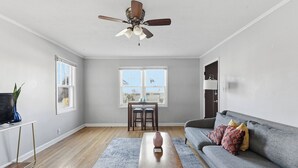 Un salon avec un ventilateur de plafond, un canapé, une table basse et un téléviseur posé sur un meuble.