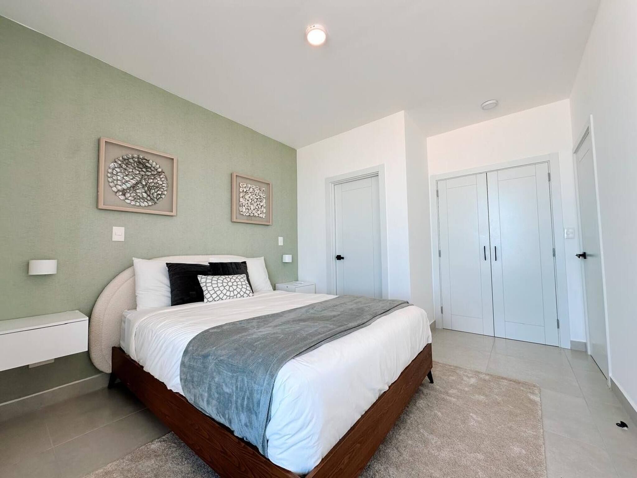Una camera da letto con un letto, due quadri appesi al muro, un comodino e un armadio.