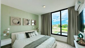 A modern bedroom with a large bed, a view of the outdoors, and a window with curtains. - Azzure Cap Cana Get Away (Punta Cana)