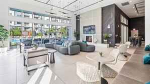 Een moderne hotel lobby met een ruime zithoek, een open haard en een televisiescherm waarop sport wordt vertoond.
