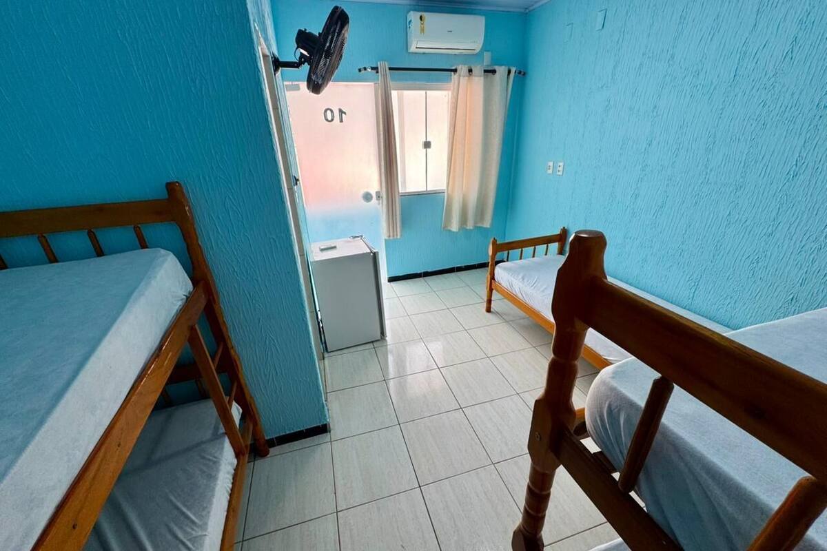 Habitación tipo dormitorio con literas, un ventilador, aire acondicionado y una ventana con cortinas.