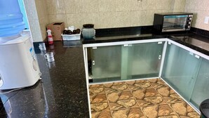 Een keuken met een zwart aanrecht, een waterdispenser, een broodrooster en een glazen kast.