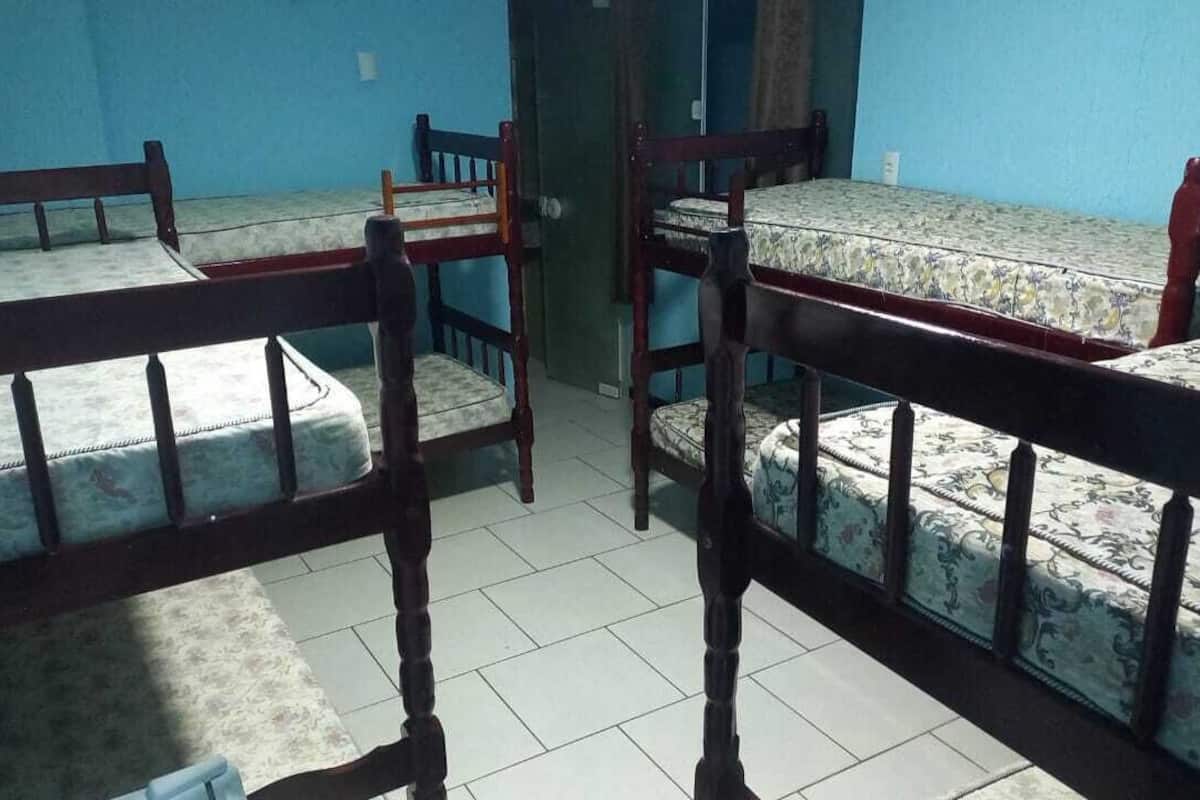 Un dormitorio con literas, sillas de madera y suelo de baldosas.