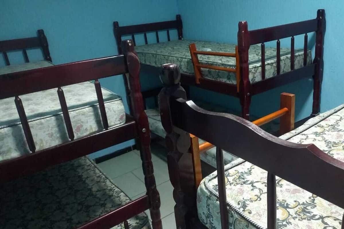 Un comedor con sillas de madera y una mesa, paredes azules y un mantel estampado.