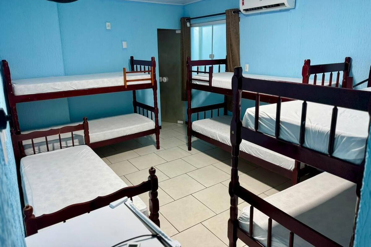 Un dormitorio con literas, un ventilador, aire acondicionado y una ventana.