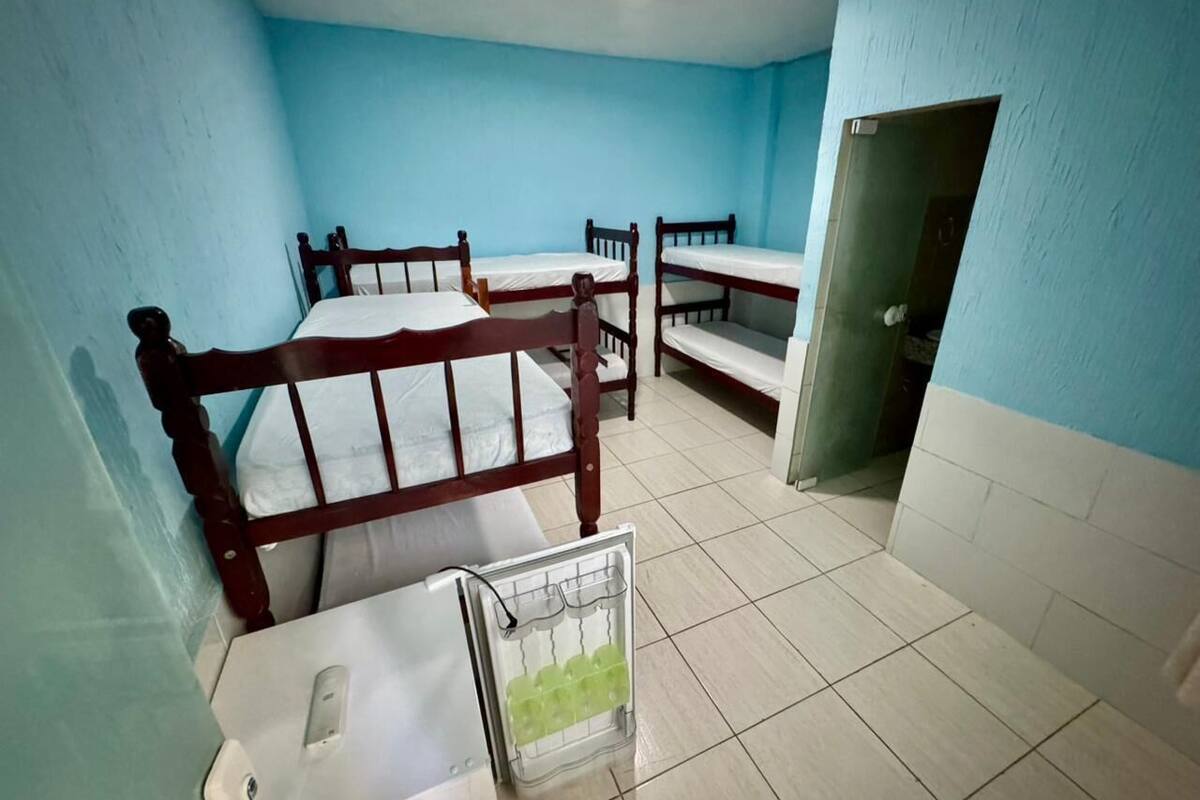 Un dormitorio con literas, una kitchenette pequeña y una puerta que da a otra habitación.