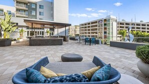 Een terras op het dak met een zithoek, een bar en uitzicht op moderne gebouwen.
