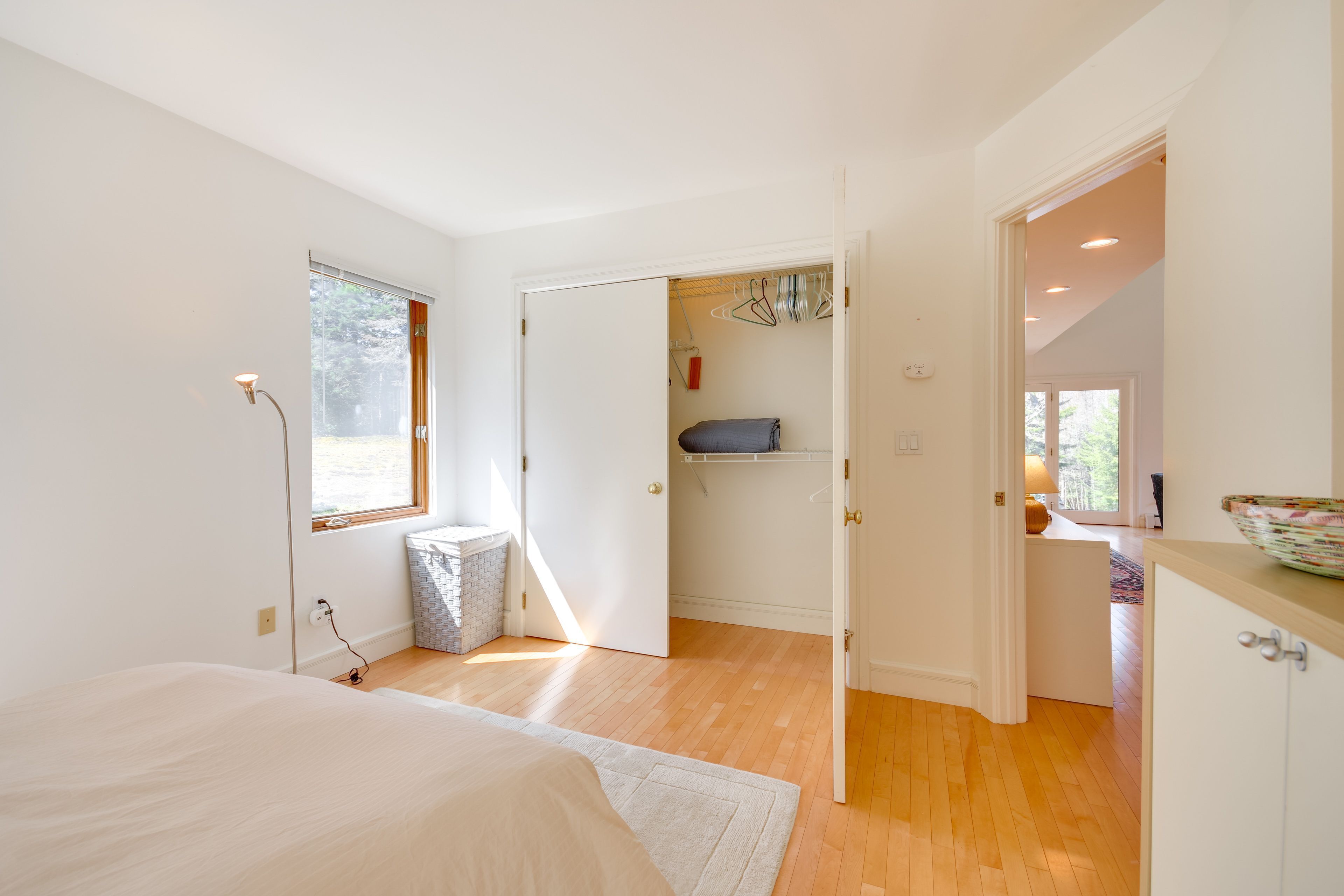 Une chambre à coucher comprenant un lit, une lampe de chevet, une fenêtre et une porte donnant sur une salle de bain.