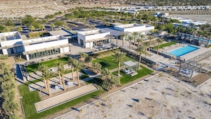 Resort com vários edifícios, piscina e áreas ajardinadas com palmeiras.