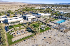 Ein Resort mit mehreren Gebäuden, einem Swimmingpool und angelegten Grünflächen mit Palmen.