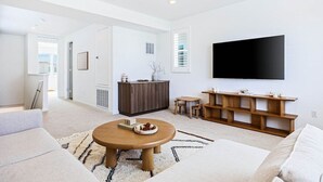 Uma sala de estar moderna com sofá, mesa de centro, TV e um móvel de entretenimento de madeira.