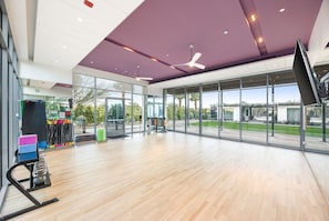 Ein geräumiger Innenbereich mit großem Fenster, Deckenventilatoren und Trainingsgeräten.