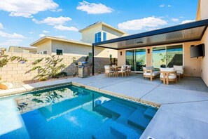 Une maison moderne dotée d’une piscine, d’un espace salon extérieur et d’un patio couvert.