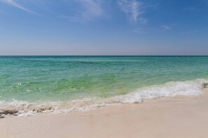Ein Strand mit klarem türkisblauem Wasser und sanften Wellen.