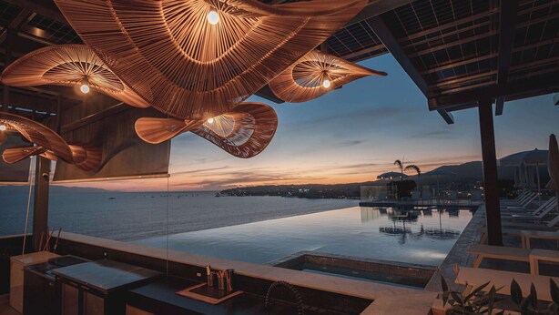 En infinitypool med utsikt över havet och stadsbilden i skymningen.