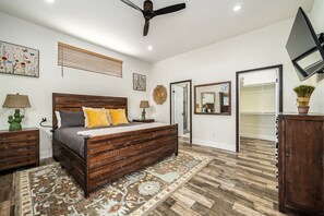 A bedroom with a wooden bed, a ceiling fan, a large mirror, and a TV mounted on the wall. - Casa Capri-Walking Distance to Old Town LQ + Park (La Quinta)