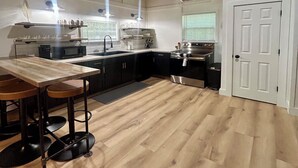 A modern kitchen with a wooden countertop, black cabinets, a stainless steel oven, and a white door.