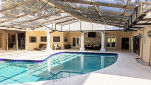 Ein überdachter Pool mit Glasdach, Steinwänden und einer gefliesten Terrasse.