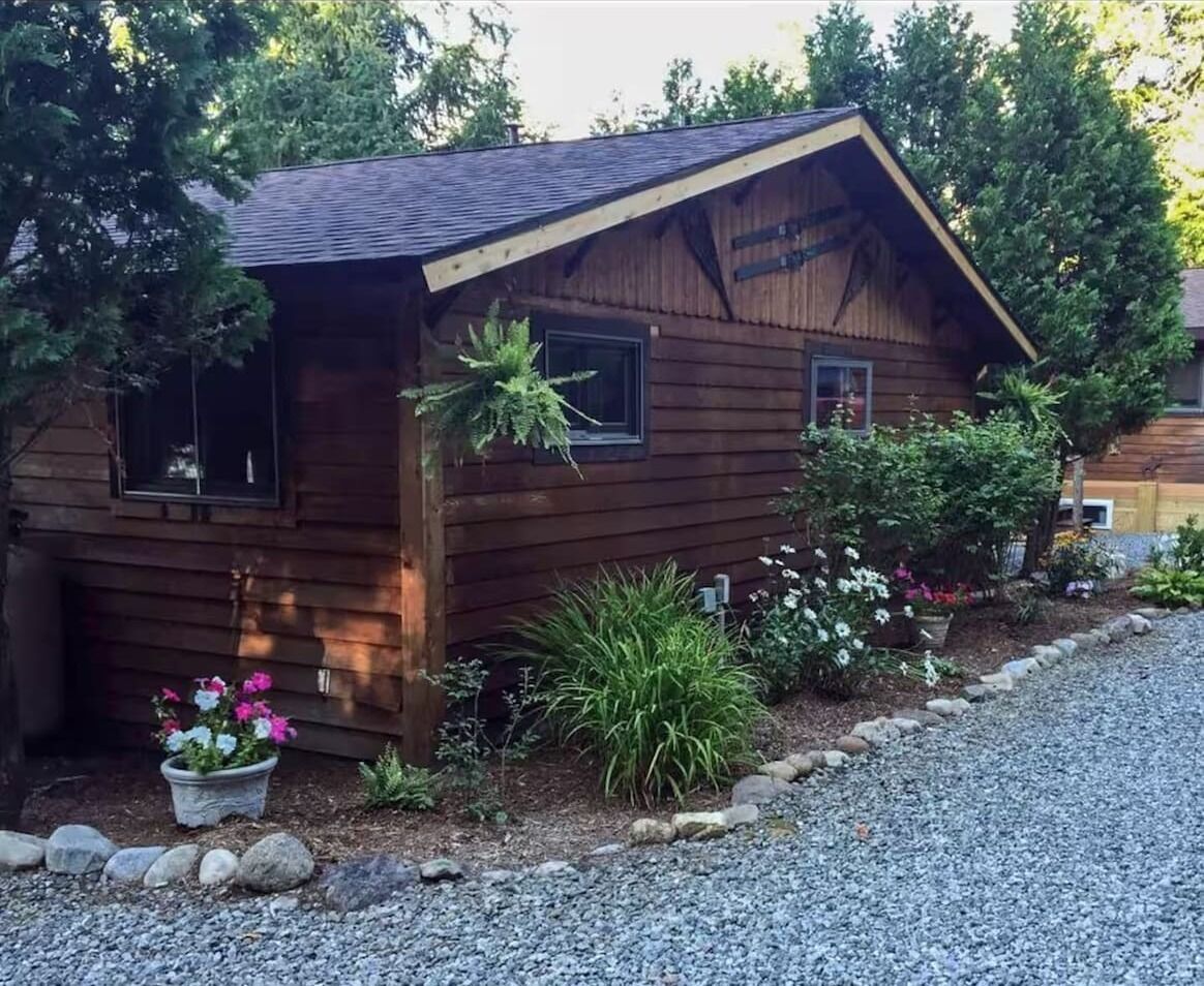 Une cabane en bois avec un toit en pente, une petite véranda et une allée gravillonnée.