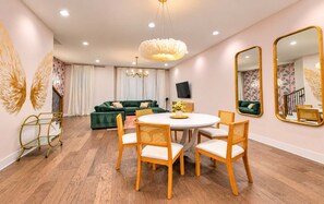 A modern living room with a round dining table, green sofa, and decorative mirrors. - 18 Beds Hot Tub Pool Table Bunk Room (Nashville)
