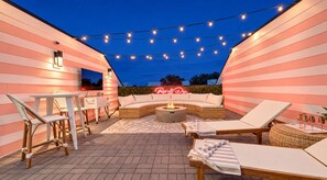 An outdoor patio with a fire pit, lounge chairs, and string lights. - 18 Beds Hot Tub Pool Table Bunk Room (Nashville)