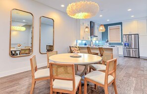 A modern kitchen with white cabinets, a stainless steel refrigerator, and a round dining table with wicker chairs. - Rosé All Day • Insta • 21 Beds • Hot Tub/Game Room (Nashville)