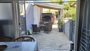 En terrasse med et bord og stole, en grill og et overdækket siddeområde.